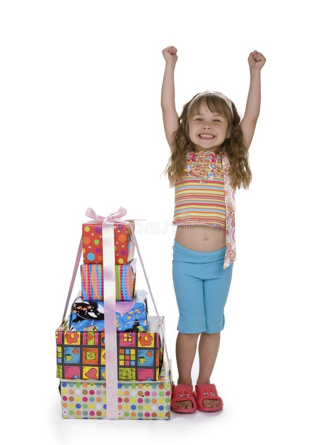 Cute girl throwing arms in the air with excitment, standing next to a stack of presents, white background. Cute girl throwing arms in the air with excitment, standing next to a stack of presents, white background.