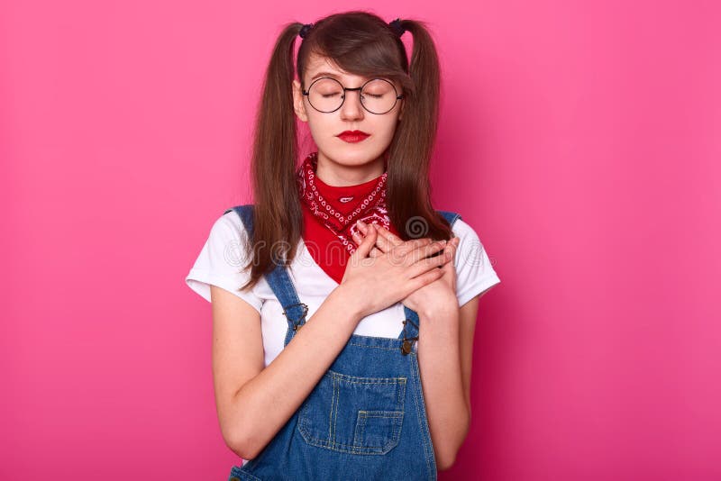 A menina encantador delgada com olhos fechados est? o cruzamento reto ambas as m?os na caixa, tentando sentir a pulsa??o do cora? fotografia de stock royalty free A menina encantador delgada com olhos fechados est? o cruzamento reto ambas as m?os na caixa, tentando sentir a pulsa??o do cora? fotografia de stock royalty free