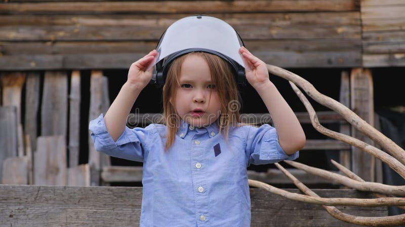 Menina engraçada em um capacete protetor de um bombeiro ou de uma salva-vidas