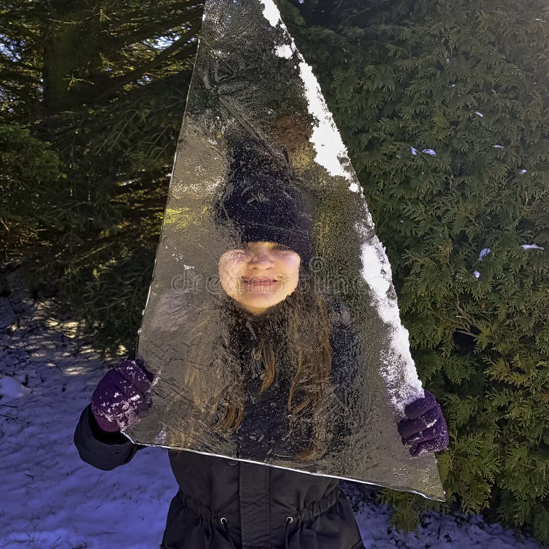 Menina escondida atrás da parte de banquisa de gelo em Choczewo, Pomerania, Polônia imagem de stock Menina escondida atrás da parte de banquisa de gelo em Choczewo, Pomerania, Polônia imagem de stock