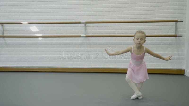 A menina está executando movimentos da dança na escola do bailado