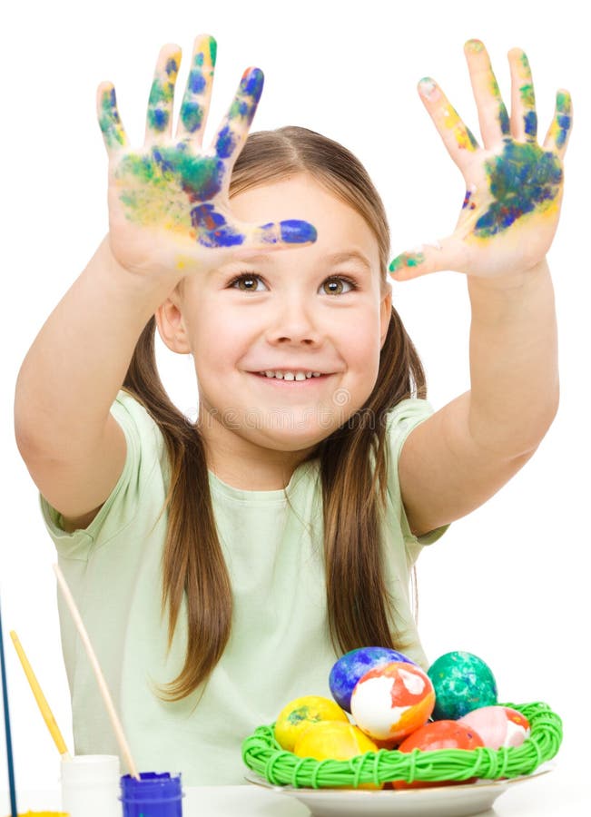 A menina está pintando os ovos que preparam-se para a Páscoa foto de stock A menina está pintando os ovos que preparam-se para a Páscoa foto de stock