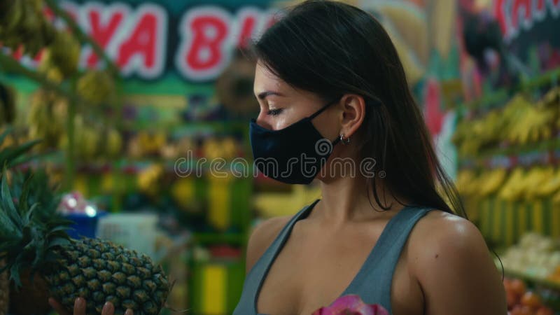 Menina europeia escolhe frutas orgânicas numa loja com abacaxi na mão