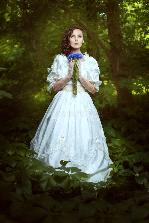 Menina fantástica em um vestido branco com centáureas das flores fotografia de stock royalty free Menina fantástica em um vestido branco com centáureas das flores fotografia de stock royalty free