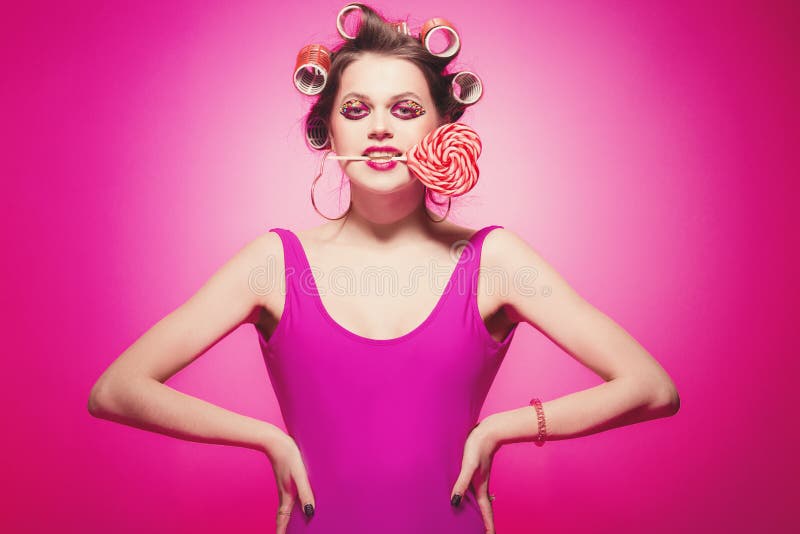 Menina feliz com o coração dos doces que levanta no fundo cor-de-rosa no corpo, com os encrespadores na cabeça Mulher 'sexy' b fotografia de stock Menina feliz com o coração dos doces que levanta no fundo cor-de-rosa no corpo, com os encrespadores na cabeça Mulher 'sexy' b fotografia de stock