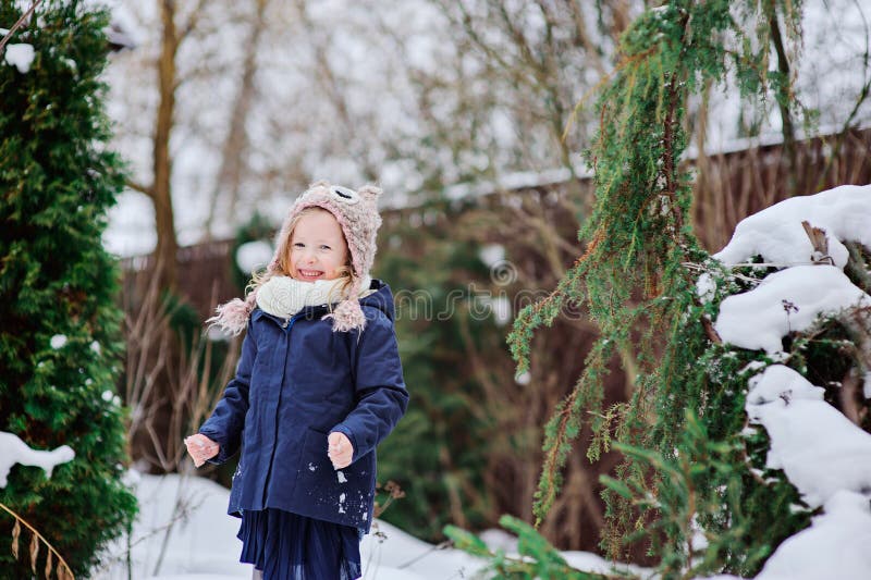 Happy child girl in knitted hat plays in winter snowy garden. Happy child girl in knitted hat plays in winter snowy garden