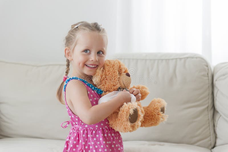 Menina feliz da criança que joga com seu urso de peluche em casa fotografia de stock royalty free Menina feliz da criança que joga com seu urso de peluche em casa fotografia de stock royalty free