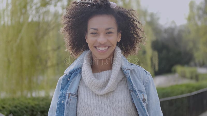 Menina feliz e sorrindo da ra?a misturada com corte de cabelo afro que anda no parque