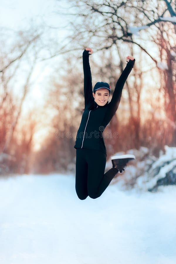 Menina feliz no equipamento do Sportswear que salta na neve foto de stock royalty free Menina feliz no equipamento do Sportswear que salta na neve foto de stock royalty free