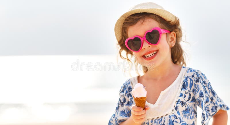 Menina feliz que come o gelado na praia fotografia de stock royalty free Menina feliz que come o gelado na praia fotografia de stock royalty free
