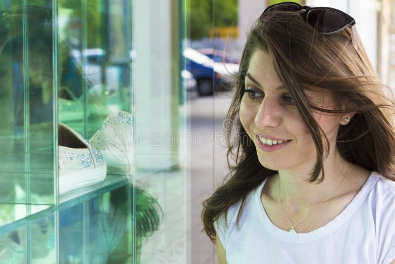 Menina feliz que olha na janela da loja imagem de stock Menina feliz que olha na janela da loja imagem de stock