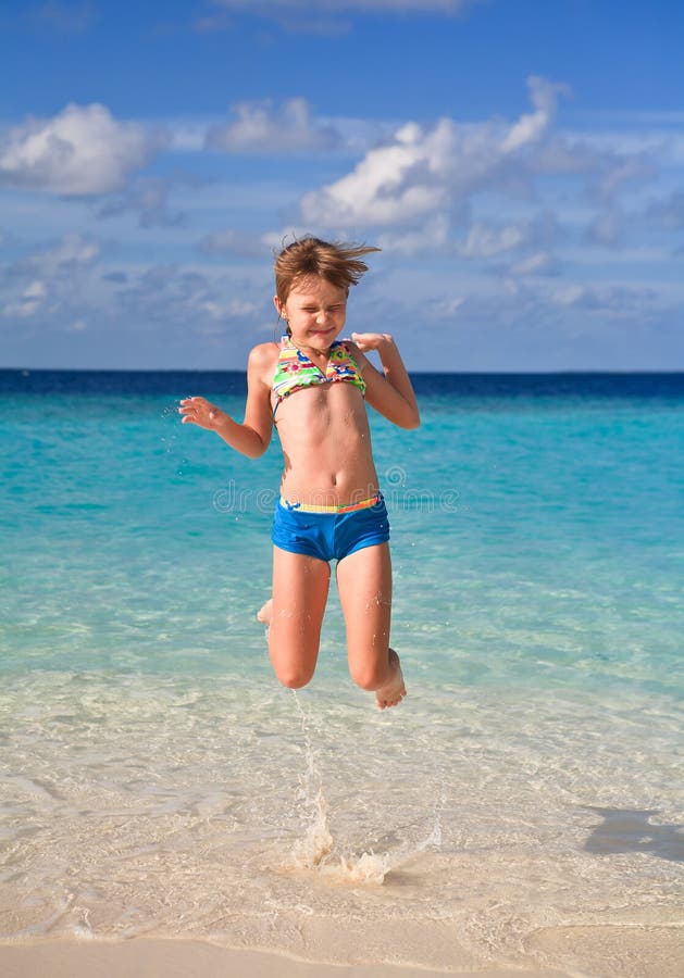 Menina feliz que salta na praia fotografia de stock Menina feliz que salta na praia fotografia de stock