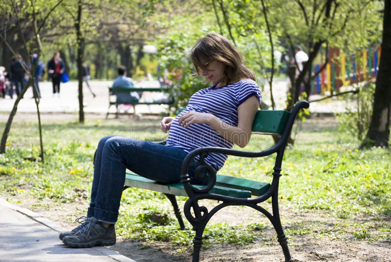 Rapariga grávida num banco imagens de stock