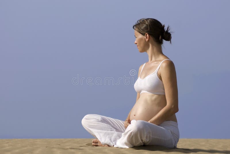 Rapariga grávida sentada na areia fotos de stock