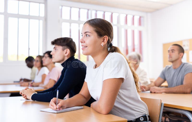 Menina interessada ouvindo e tomando notas de palestra na universidade fotografia de stock