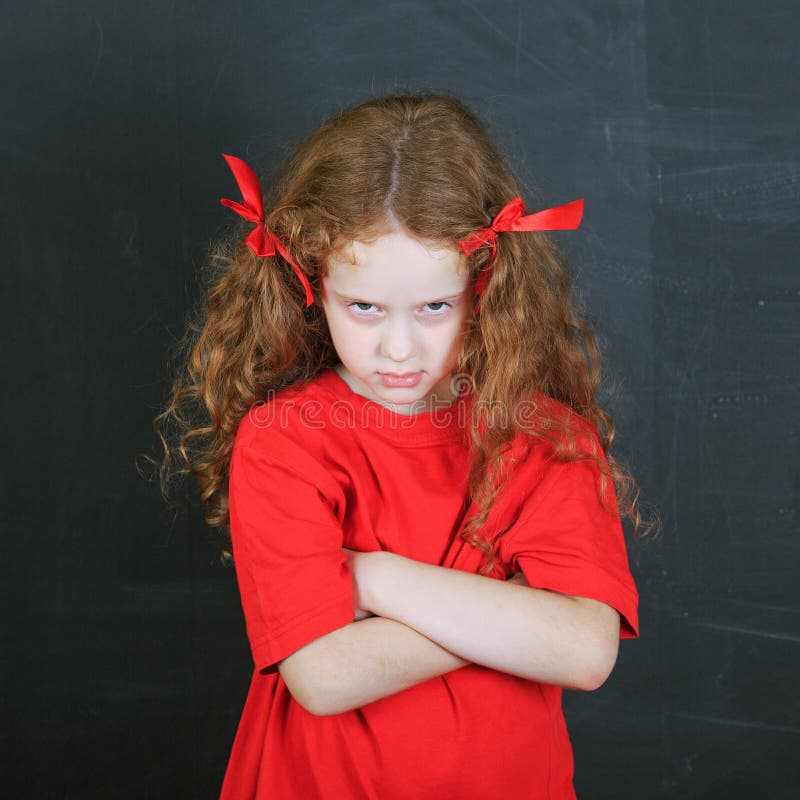 Menina irritada no t-shirt vermelho Caráter da criança foto de stock Menina irritada no t-shirt vermelho Caráter da criança foto de stock