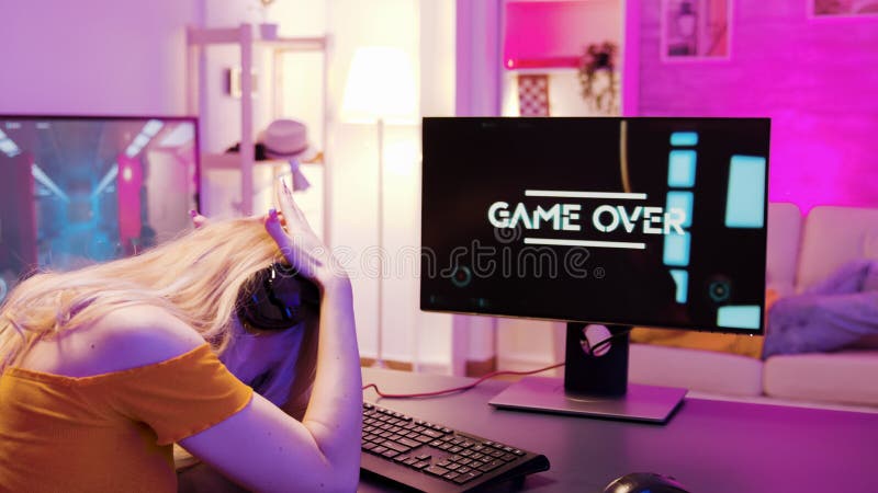 Menina loira jogando jogos de tiro online, sentada na cadeira de jogo.  namorado usando óculos de realidade virtual.