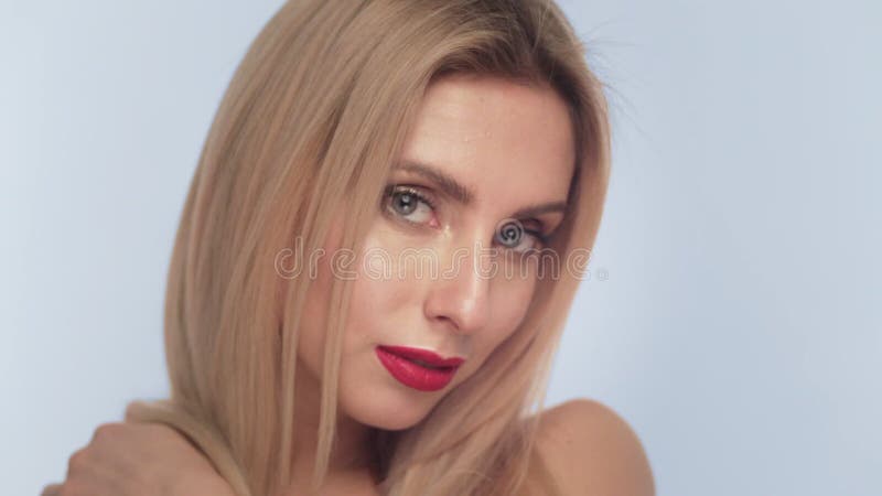 Menina loura bonita com o cabelo longo, composição clássica e os bordos vermelhos levantando no estúdio Face da beleza filme