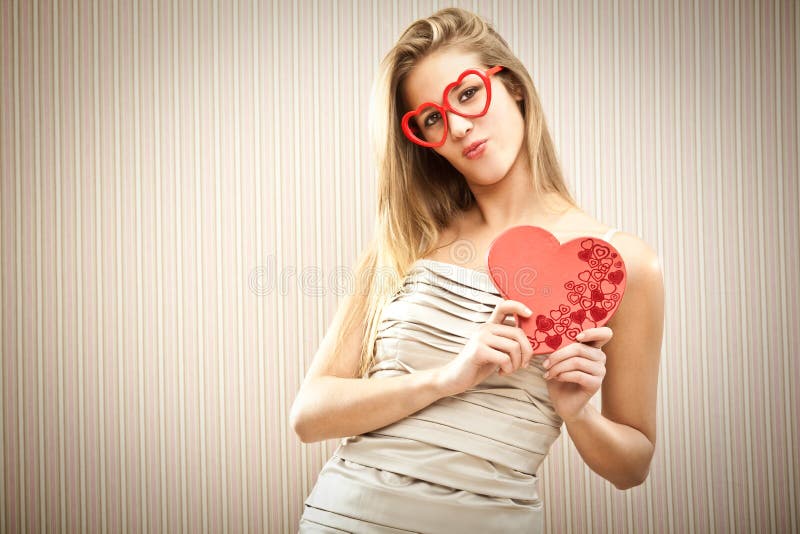 Menina loura bonita com vidros do coração com o presente do amor da caixa do chocolate imagem de stock Menina loura bonita com vidros do coração com o presente do amor da caixa do chocolate imagem de stock