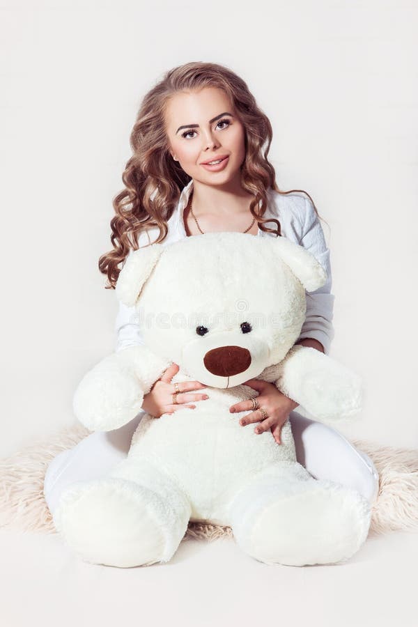 Menina loura consideravelmente escura que abraça o urso de peluche imagem de stock royalty free Menina loura consideravelmente escura que abraça o urso de peluche imagem de stock royalty free