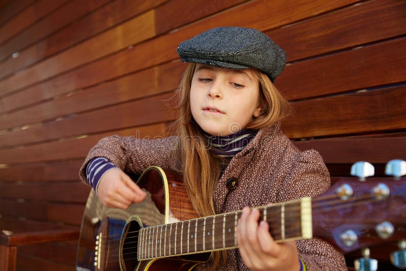 Menina loura da criança que joga a guitarra com boina do inverno foto de stock Menina loura da criança que joga a guitarra com boina do inverno foto de stock