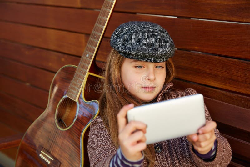 Menina loura da criança que toma a guitarra do selfie e a boina do inverno imagens de stock royalty free Menina loura da criança que toma a guitarra do selfie e a boina do inverno imagens de stock royalty free