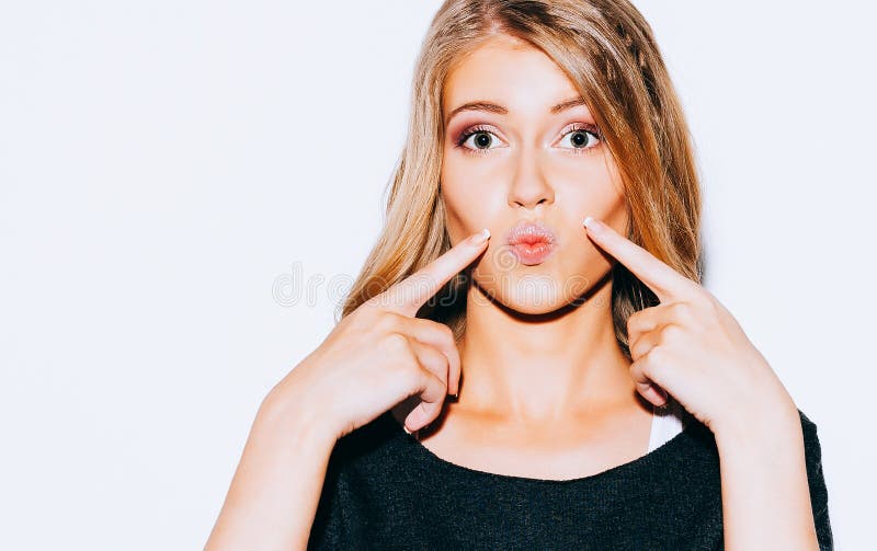 A menina loura nova bonita que levanta na camiseta e no beijo branco do short e o vermelho dos bordos faz Aponta um dedo em seus imagens de stock A menina loura nova bonita que levanta na camiseta e no beijo branco do short e o vermelho dos bordos faz Aponta um dedo em seus imagens de stock