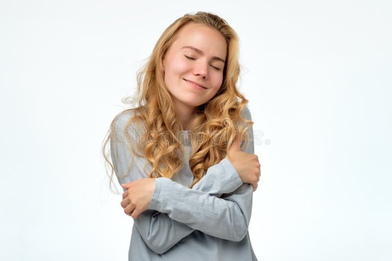 Menina loura nova do adolescente que abraçam-se oneself que está feliz e sorriso seguro fotografia de stock royalty free Menina loura nova do adolescente que abraçam-se oneself que está feliz e sorriso seguro fotografia de stock royalty free