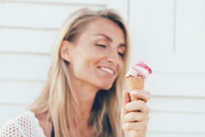 Menina loura que come o gelado de derretimento em um cone fotos de stock Menina loura que come o gelado de derretimento em um cone fotos de stock