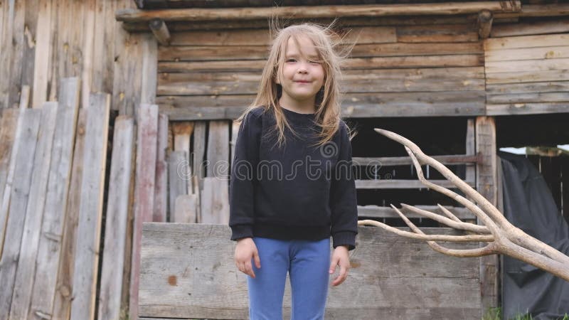 A menina louro nova bonita levanta em uma paisagem de madeira do camponês