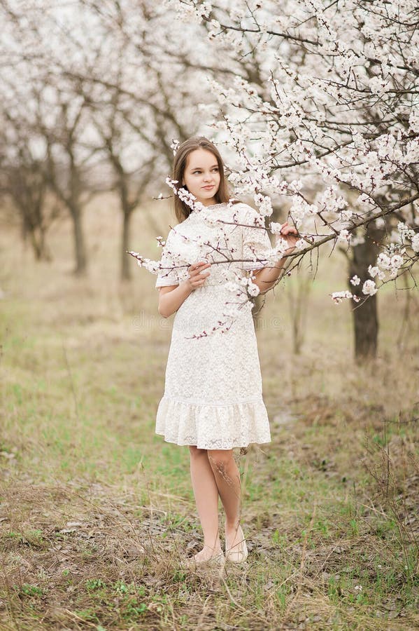 A menina macia nova bonita no jardim em um dia de mola, pétalas da flor da flor que caem da árvore, fechou seus olhos e guardar imagem de stock A menina macia nova bonita no jardim em um dia de mola, pétalas da flor da flor que caem da árvore, fechou seus olhos e guardar imagem de stock