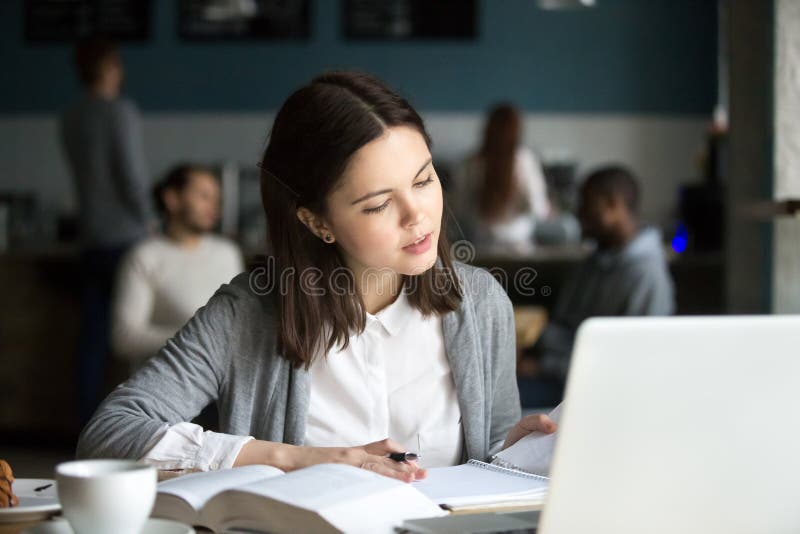 Menina milenar inteligente séria que estuda no café que prepara f foto de stock Menina milenar inteligente séria que estuda no café que prepara f foto de stock