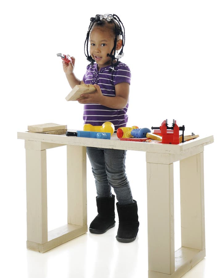 An adorable preschooler playing with toy tools on a child-sized workbench. On a white background. An adorable preschooler playing with toy tools on a child-sized workbench. On a white background.