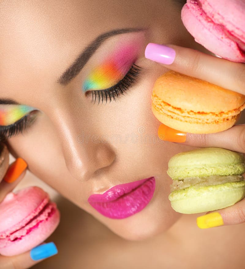 Menina modelo que toma bolinhos de amêndoa coloridos imagens de stock