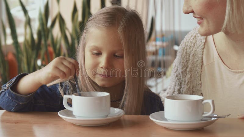 A menina move a colher no copo imagens de stock