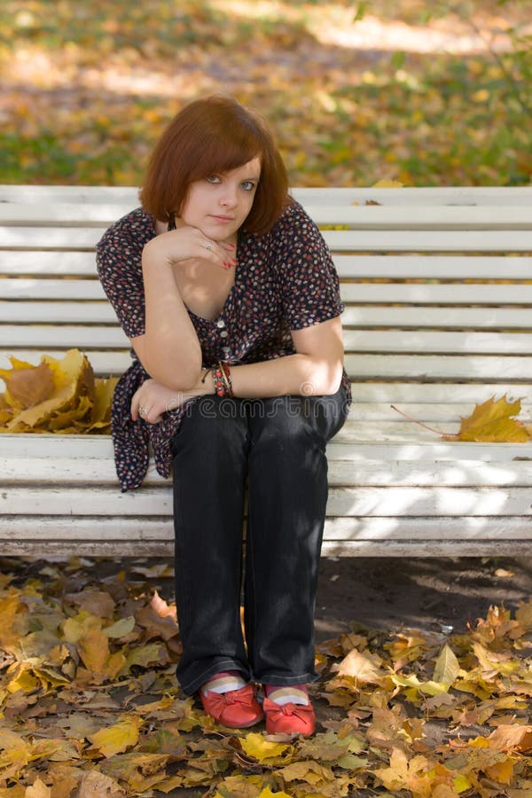 Menina no banco de parque do outono imagem de stock