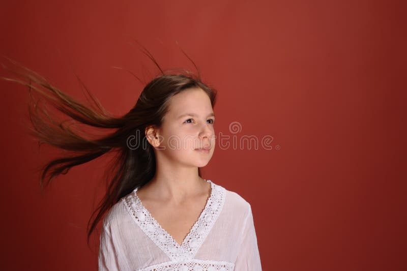 Menina num estúdio com fundo vermelho e cabelo ao vento foto de stock royalty free
