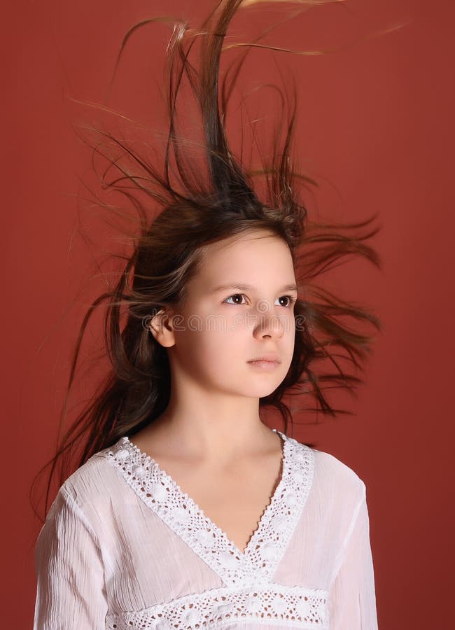 Menina num estúdio com fundo vermelho e cabelo ao vento fotografia de stock