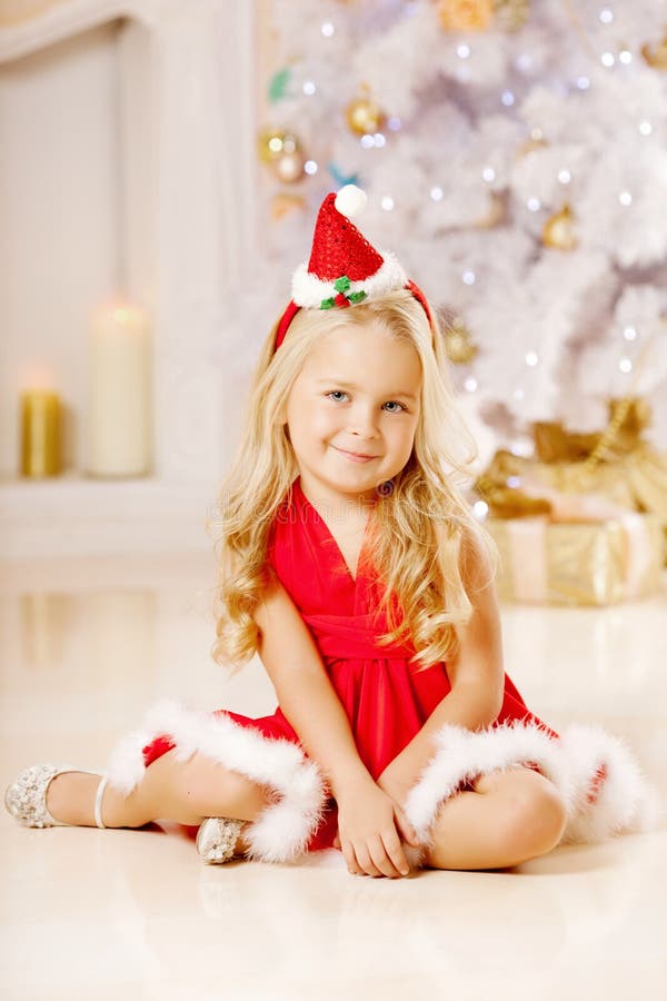Menina pequena bonita de Santa perto da árvore de Natal Menina feliz