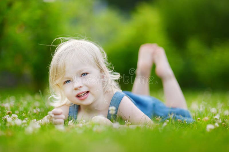 Menina pequena bonito da criança que coloca na grama imagem de stock Menina pequena bonito da criança que coloca na grama imagem de stock