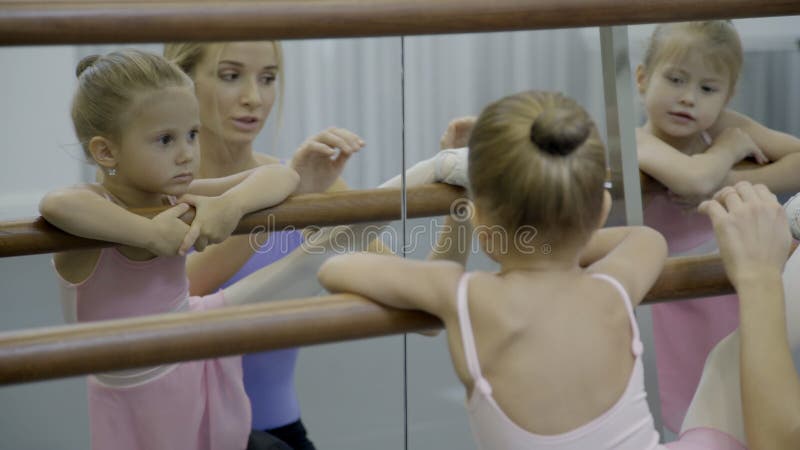 Menina pequena que faz o esticão com o professor na escola do bailado