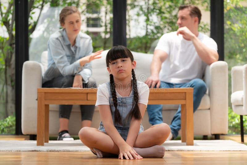 Stressed and unhappy young girl crying and trapped in middle of tension by her parent argument in living room. Unhealthy domestic lifestyle and traumatic childhood develop to depression. Synchronos. Stressed and unhappy young girl crying and trapped in middle of tension by her parent argument in living room. Unhealthy domestic lifestyle and traumatic childhood develop to depression. Synchronos