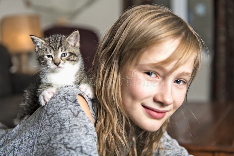 Menina Preteen de 10 anos velho com seu animal de estimação do gato no sofá fotografia de stock royalty free Menina Preteen de 10 anos velho com seu animal de estimação do gato no sofá fotografia de stock royalty free