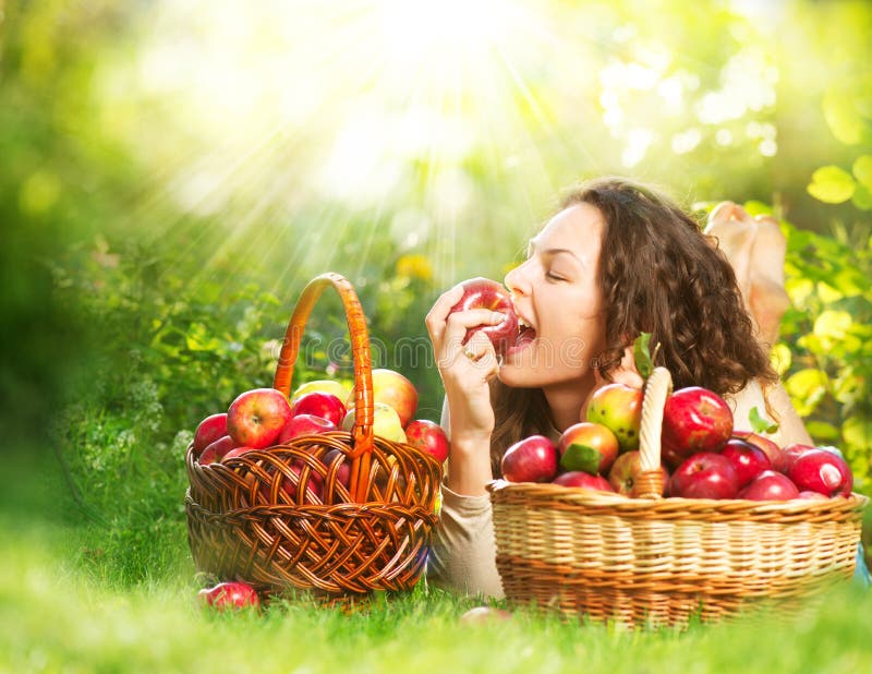 Menina que come Apple orgânico no pomar imagens de stock royalty free Menina que come Apple orgânico no pomar imagens de stock royalty free