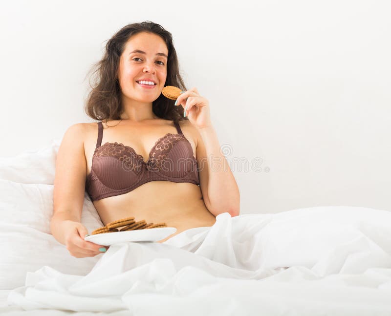 Menina que come cookies na cama fotos de stock
