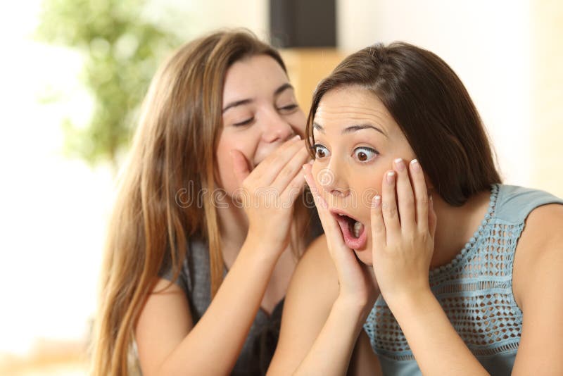Menina que diz segredos a seu amigo surpreendido imagem de stock Menina que diz segredos a seu amigo surpreendido imagem de stock