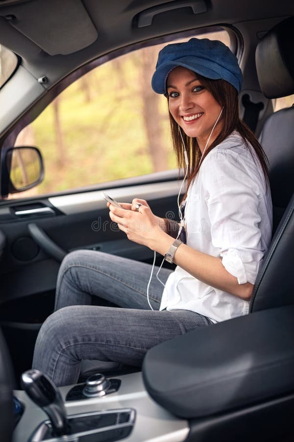 Menina que escuta a música com os fones de ouvido que movem-se no carro foto de stock Menina que escuta a música com os fones de ouvido que movem-se no carro foto de stock