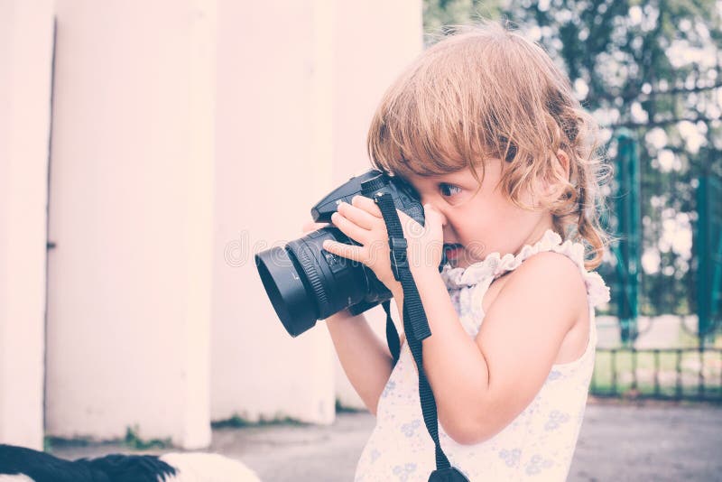 Menina que guarda uma câmera e que toma imagens imagens de stock royalty free Menina que guarda uma câmera e que toma imagens imagens de stock royalty free