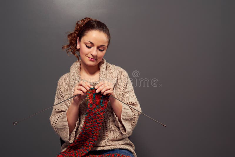 Rapariga a segurar agulhas e a tricotar um cachecol imagem de stock royalty free