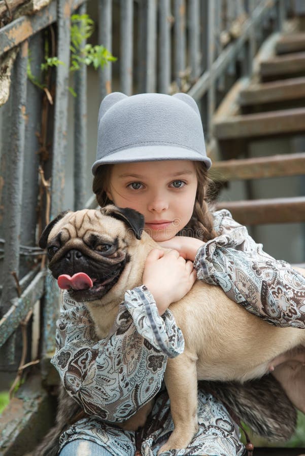 Little kid girl playing with her pug dog outdoors in rural areas in summer. Little kid girl playing with her pug dog outdoors in rural areas in summer.